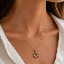 Gold necklace with a Star of David pendant on a person wearing a white shirt.