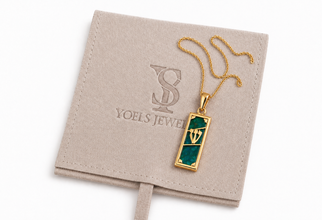 Gold necklace with a green pendant on a Yoels Jewelry branded card.