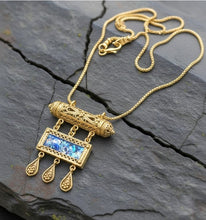 Gold  filigree amulet necklace with a roman glass  on a dark stone surface