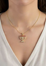 Gold necklace with a Menorah pendant on a model wearing a white top.