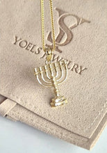 Gold menorah pendant necklace on a branded card