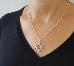 Silver Star of David necklace on a person wearing a black shirt