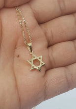 Gold Star of David necklace held in a hand