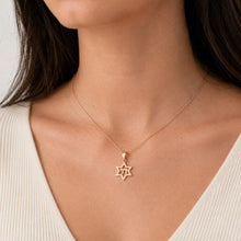 Gold necklace with a star pendant on a person wearing a white top.