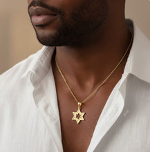 Man wearing a gold necklace with a star pendant against a neutral background