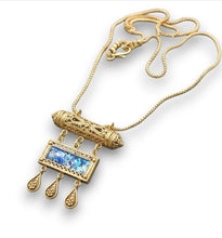 Gold  filigree amulet necklace with a roman glass  on a dark stone surface