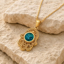 14K Gold Hamsa Pendant with natural Eilat Stone on stone background, luxury Judaica jewelry made in Israel