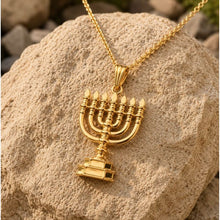 Gold menorah pendant necklace on a rock