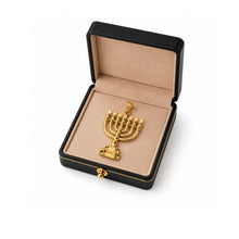 Gold menorah pendant in a black jewelry box on a white background