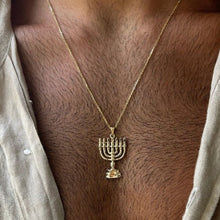 Gold menorah pendant necklace on a person's neck