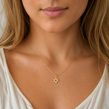 Close-up of a woman wearing a gold necklace with a star pendant.