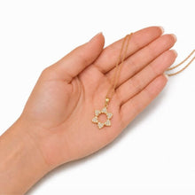 Hand holding a gold necklace with a star-shaped pendant on a white background