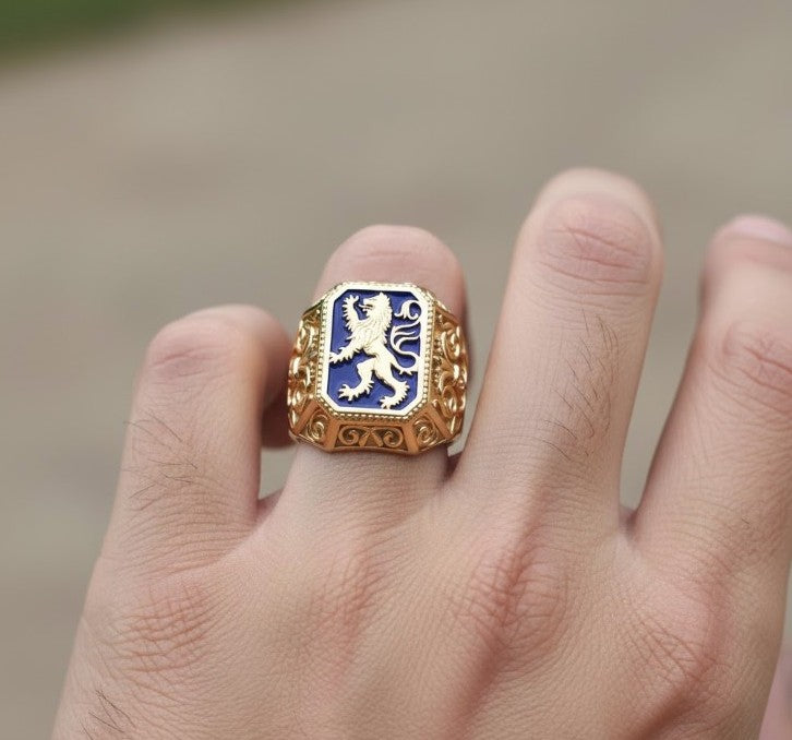 Gold ring with a blue emblem featuring a lion on a finger against a blurred background