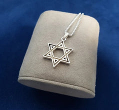 Silver Star of David necklace on a gray cushion with a blue background