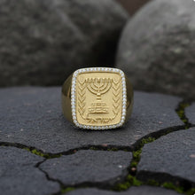 Gold ring with Menorah design on a textured surface