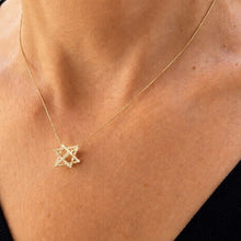 Gold necklace with a star-shaped pendant on a person's neck