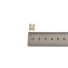 Gold geometric pendant next to a ruler on a white background