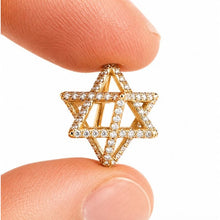 Gold Star of David pendant held between two fingers on a white background