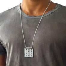 A man wearing a 14k gold hoshen pendant with ornaments and 12 colored gems on a grey shirt.