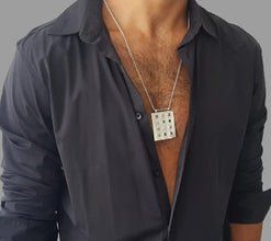 A man wearing a 14k gold hoshen pendant with ornaments and 12 colored gems on a grey shirt.