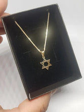 Gold necklace with Star of David pendant on a black display box.