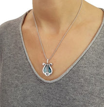 A 925 sterling silver harp pendant featuring a green eilat stone in the center, with star of david pendant on the side.