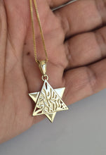 A gold pendant necklace featuring a Star of David with the Hebrew word 'Shin' engraved in the center, held in a person's hand.