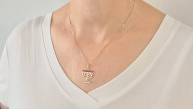 Gold menorah pendant necklace on a white shirt