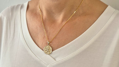 Gold necklace with a pendant on a white shirt
