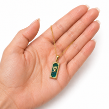 Gold necklace with eilat stone pendant held in a hand on a white background