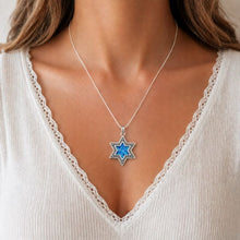 Star-shaped blue pendant necklace on a person wearing a white top.