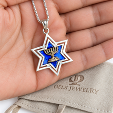 Silver Star of David necklace with gold Menorah resting in a hand