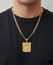 Gold chain necklace with a pendant on a black shirt