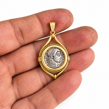 Gold pendant with silver Roman coin reproduction in a cream jewelry box.