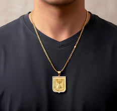 Gold necklace with a pendant worn by a person against a neutral background