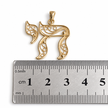 gold chai pendant on ruler 