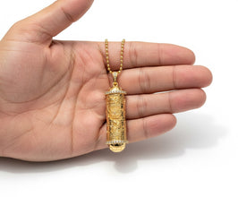 Gold necklace with a pendant held in a hand on a white background