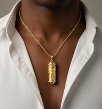 Gold necklace with a pendant worn by a person in a white shirt.