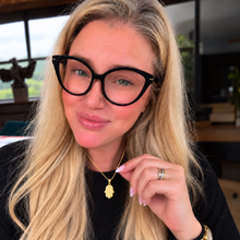 Woman wearing a small polished 14K yellow gold Hamsa pendant on a gold chain