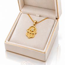 14K gold Hamsa pendant with diamond Star of David in an ivory jewelry box.