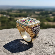 Gold ring with gemstones on a rock with a blurred landscape background