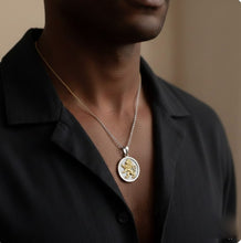 Person wearing a necklace with a lion pendant on a plain background