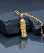 Gold pendant necklace on a dark stone surface