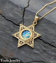 Gold star-shaped pendant with blue gemstone on a dark stone surface, branded 'Yoels Jewelry'.