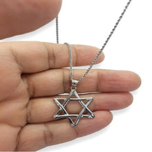 Silver Star of David necklace held in a hand against a white background