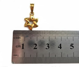 Gold star-shaped pendant next to a ruler for scale on a white background