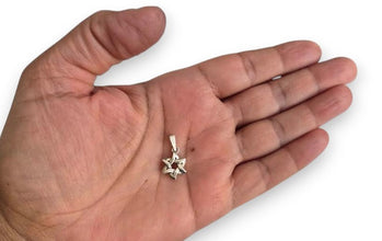 Silver star-shaped pendant held in a hand on a white background