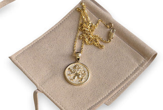 Gold necklace with a round pendant on a beige jewelry display