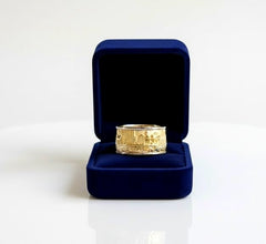Gold ring in a blue velvet box on a white background