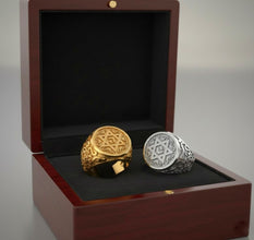 Two rings, one gold and one silver, in a wooden box with black interior.